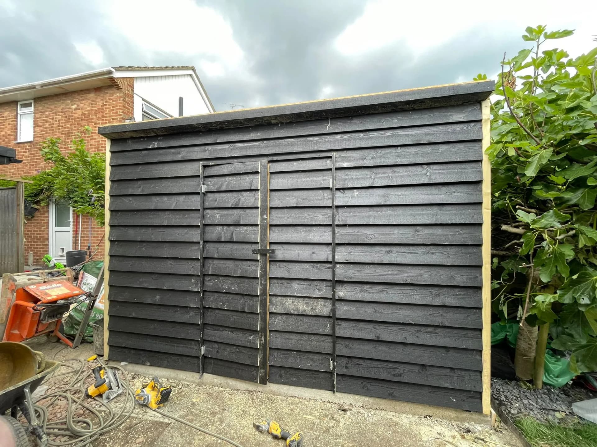 Bespoke garden workshop clad in black feather-edge board with twin doors