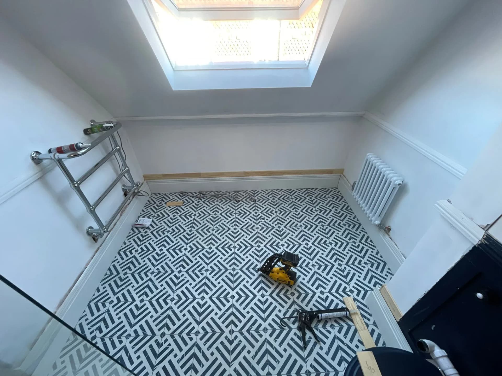 Loft bathroom with a bold monochrome geometric tiled floor and a rooflight above